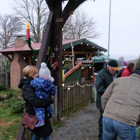 mehrere Personen an einem Torbogen bei der Blockhütte von Brand's Weihnachtsbäume