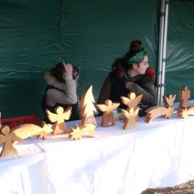 zwei Mädchen an einem Verkaufstisch mit weihnachtlicher Holzdekoration